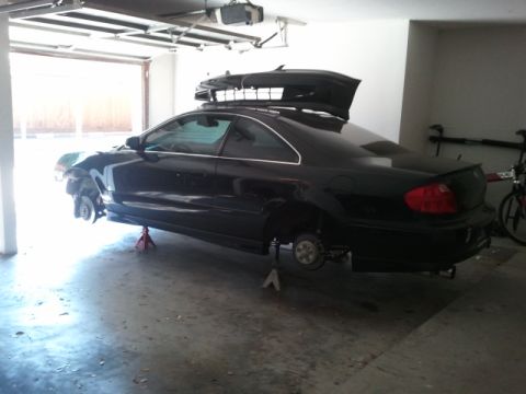 2008 Subaru Legacy - Black coupe on jack stands in a garage, front and rear wheels removed.