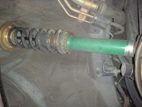 2008 Subaru Legacy - Close-up of a green suspension strut and coilover spring assembly, showing mechanical components.