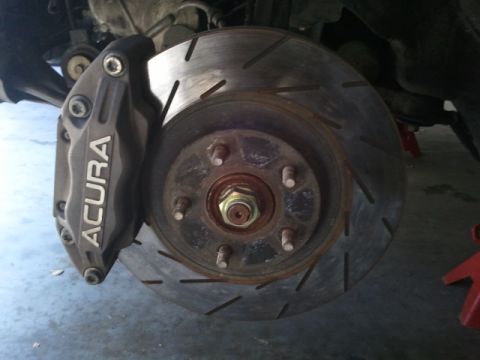2008 Subaru Legacy - Close-up of an Acura brake caliper and a slotted rotor, indicating a focus on automotive performance parts.