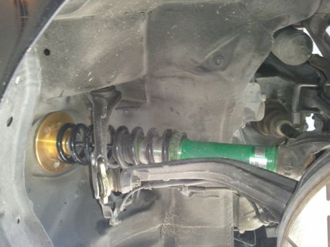 2008 Subaru Legacy - Aftermarket coilover suspension part with gold perch and green shock body.