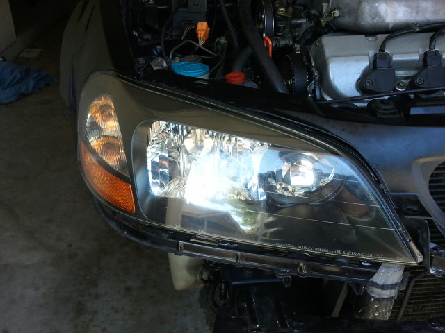 Close-up of a car's front headlight assembly and part of the engine bay. Text on headlight reads 'STANLEY'
