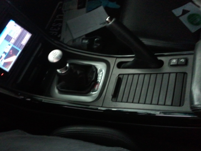 Car interior showing gear shift, handbrake, and infotainment screen