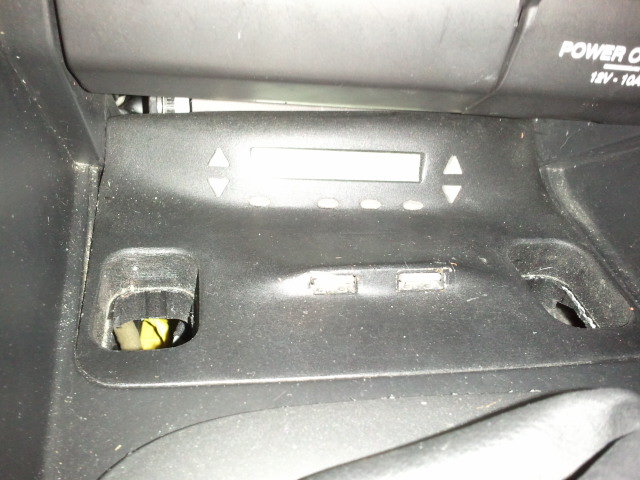 Car dashboard with digital display and buttons, showing power outlet text