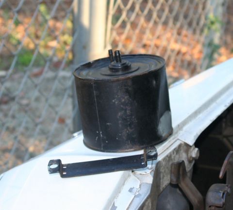 1976 Ford Ranchero - Vacuum canister and mounting bracket on a car fender.