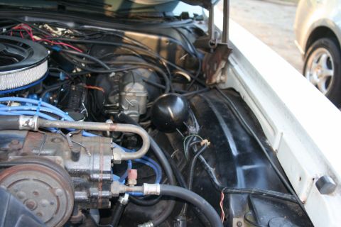 1976 Ford Ranchero - The engine bay of a white vehicle is shown, with various components and wiring visible.