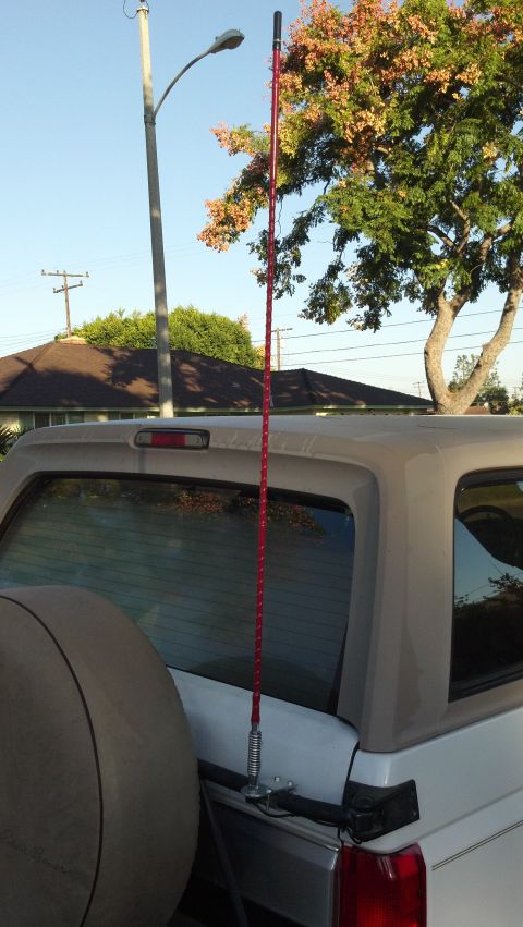 1996 Ford Bronco - Rear view of a 1996 Ford Bronco, equipped with a spare tire and a prominent red CB antenna mounted on the tailgate.