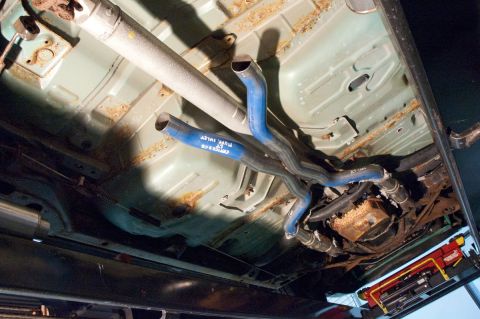 1998 Ford Crown Victoria - The underside of a vehicle shows a custom exhaust system with blue-painted pipes and visible text on the tubing.