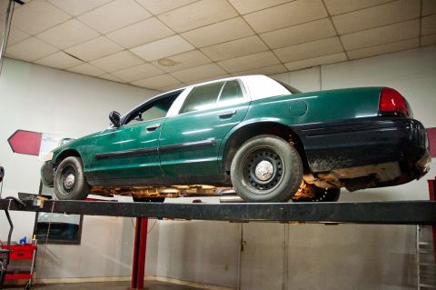 1998 Ford Crown Victoria - A green and white 1998 Ford Crown Victoria is shown on a vehicle lift, likely in a repair shop.
