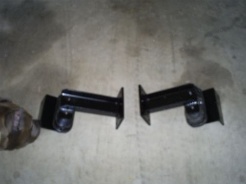 1992 Ford Bronco - A pair of black metal brackets with rubber isolators are shown on a concrete surface.