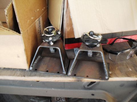 1986 Ford Bronco - Two custom-made jack stands sit on a wooden surface next to cardboard boxes and safety glasses.