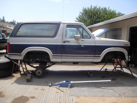 1986 Ford Bronco - Ford Bronco undergoing maintenance, with suspension components removed and vehicle elevated.