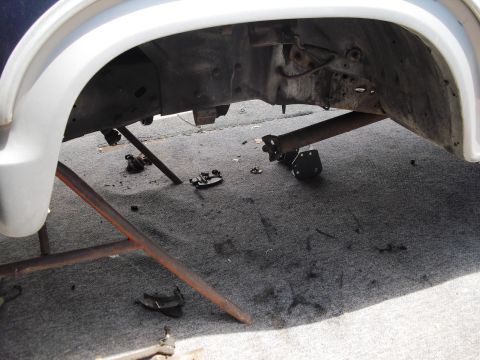 1986 Ford Bronco - The underside of a vehicle is shown with components removed and lying on the ground.