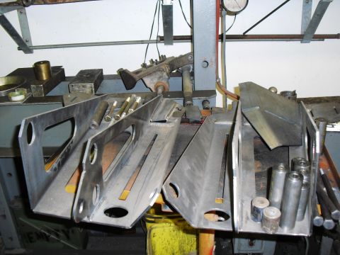1986 Ford Bronco - Metal fabrication parts and hardware are laid out on a workbench.