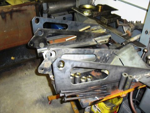 1986 Ford Bronco - Metal brackets and hardware are piled on a workbench in a workshop.