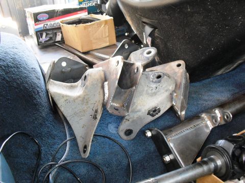 1986 Ford Bronco - Various metal suspension components and a driveshaft are laid out, possibly for installation or repair.