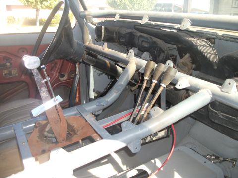 1979 Ford Bronco - The interior of a vehicle shows a complex roll cage and multiple shifters, with the steering wheel and dashboard visible.