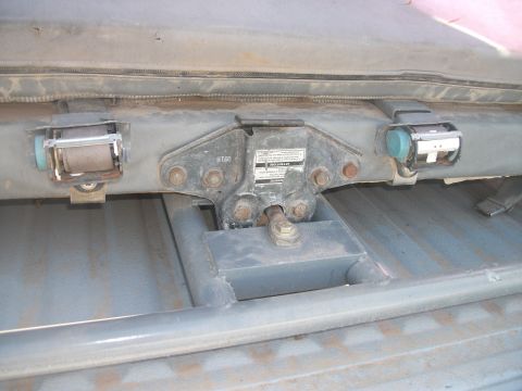 1979 Ford Bronco - Close-up view of seatbelt retractors and roll cage mounting hardware inside a vehicle.
