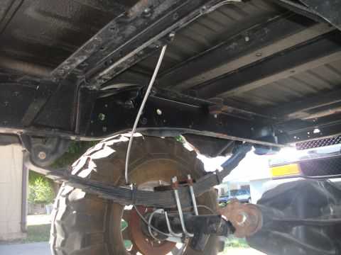 1979 Ford Bronco - The underside of a vehicle with large tires is visible, with leaf springs and frame components in focus.