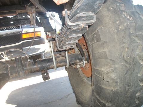 1979 Ford Bronco - This photo shows the rear suspension and axle of a vehicle, with another vehicle partially visible in the background.