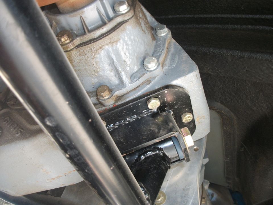 Silver transfer case housing bolted to fabricated black steel crossmember bracket