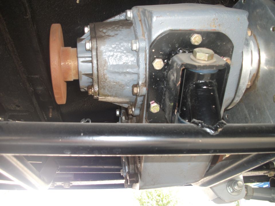 Gray transfer case with rusty output flange bolted to a black crossmember mount