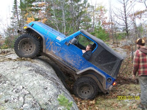1988 Ford F-250 - Jeep Wrangler navigating a difficult rocky obstacle on an off-road trail.