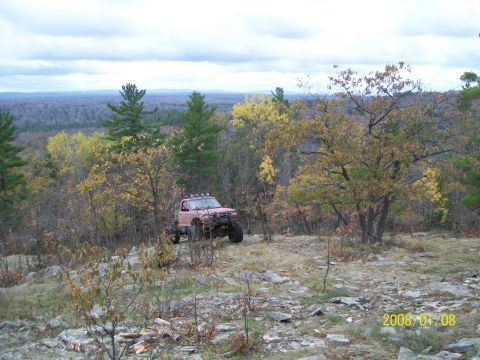 1988 Ford F-250 - A modified truck navigates a challenging off-road terrain during the fall season.