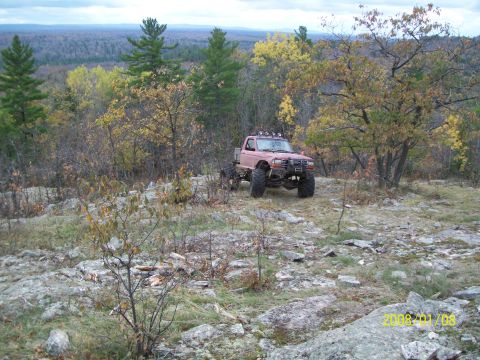 1988 Ford F-250 - This modified pickup truck navigates a rocky, wooded landscape during the autumn season.