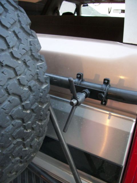 1996 Ford Bronco - Close-up of a spare tire and the rear exterior panel of a vehicle, showing a latching mechanism.