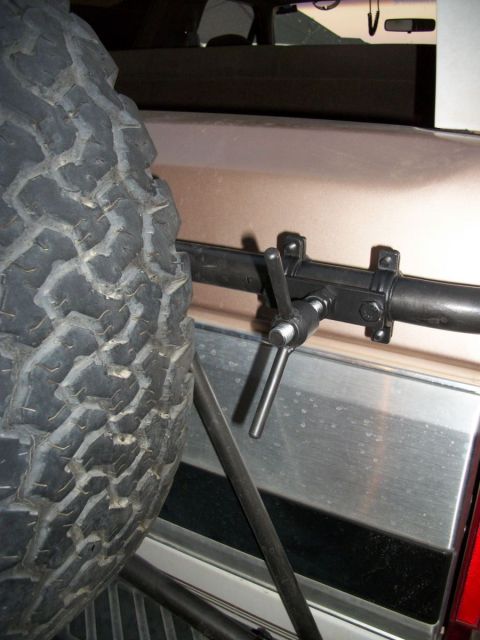 1996 Ford Bronco - Close-up of a spare tire and its mounting mechanism on a vehicle's exterior.