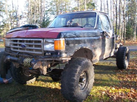 1988 Ford F-250 - Modified Ford pickup truck with large tires and lifted suspension sits in a grassy area.