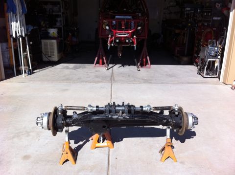 Suzuki Samurai - A vehicle's front axle assembly is displayed on jack stands in a garage setting.