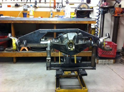 Suzuki Samurai - Custom fabricated front axle assembly mounted on a stand in a workshop setting.