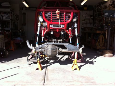 Suzuki Samurai - The front axle and suspension of a custom off-road vehicle are supported by jack stands in a garage.