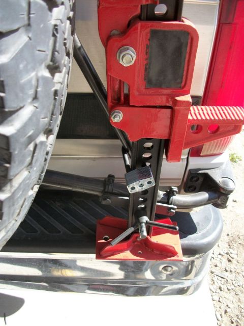 1996 Ford Bronco - A red hi-lift jack is mounted to a spare tire carrier and secured with a padlock.