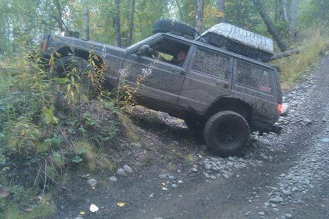 1998 Jeep Cherokee - This Jeep Cherokee is navigating a challenging off-road path with steep inclines and loose rocks.