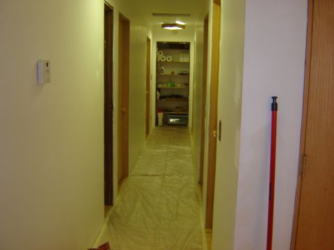 1984 Ford Mustang - A long hallway is covered in plastic sheeting, suggesting renovation or cleaning is in progress.