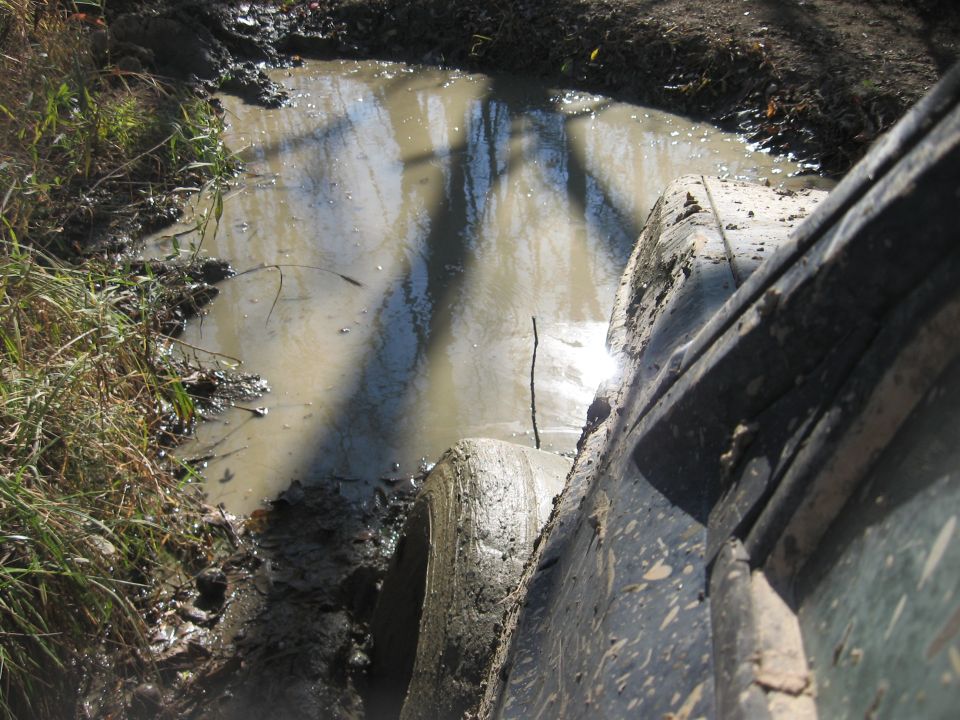 Off-road tire deep in mud, Supermotors.net logo visible