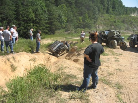 1987 Jeep Comanche - Several off-road vehicles are seen on a dirt track, with one vehicle stuck in a ditch while others observe.