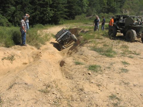 1987 Jeep Comanche - Spectators watch as an off-road vehicle tackles a challenging dirt obstacle during an outing.