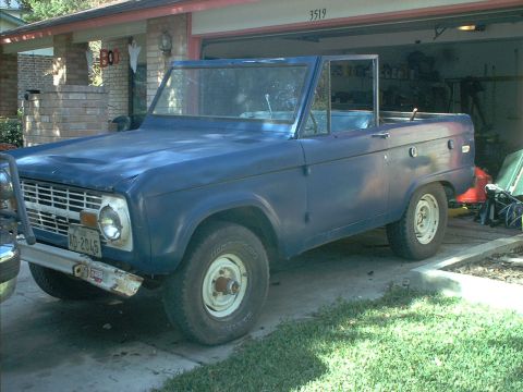 1971 Ford Bronco - A blue 1971 Ford Bronco is parked in a driveway, partially in front of an open garage door.
