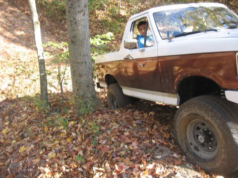 1987 Jeep Comanche - A 1987 Jeep Comanche navigates an off-road trail surrounded by trees and fallen leaves.