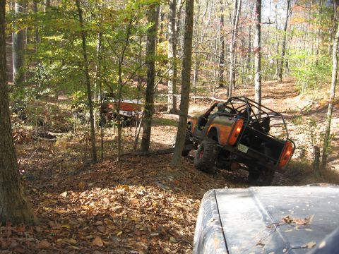 1987 Jeep Comanche - Off-roading in a forest with multiple vehicles navigating a dirt path.