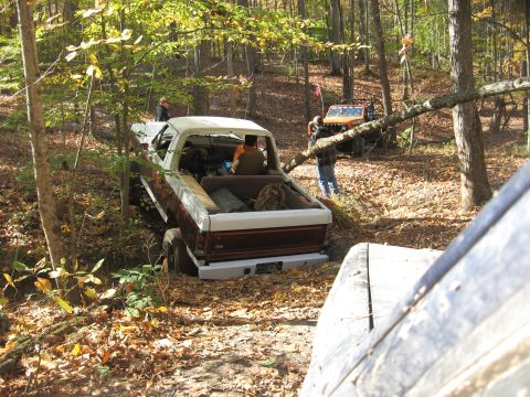 1987 Jeep Comanche - A Jeep pickup truck navigates an off-road trail with another vehicle visible in the background.