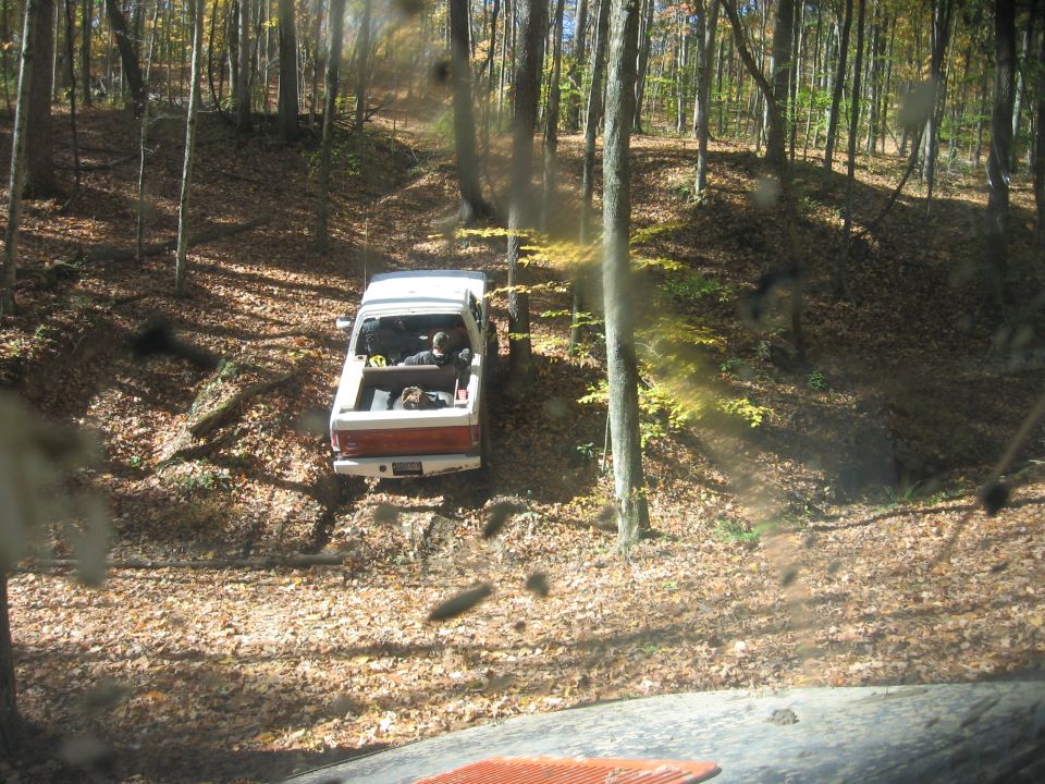 1987 Jeep Comanche driving on a leaf-covered trail in a forest