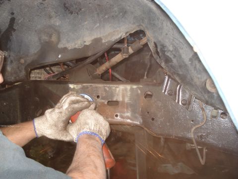 1980 Ford Bronco - A person grinds metal on a vehicle's frame, with visible wiring and suspension components.