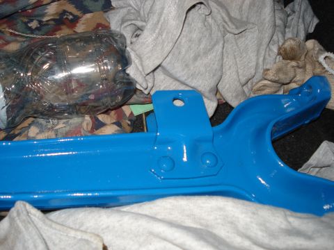 1980 Ford Bronco - A blue painted suspension component is shown, possibly for a Ford Bronco, with a plastic bottle and fabric in the background.