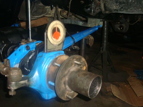 1980 Ford Bronco - Close-up of a vehicle's front axle assembly, with a gauge measuring alignment.