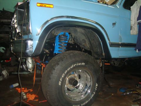 1980 Ford Bronco - Front quarter view of a light blue SUV with a lifted suspension and a Bronco emblem on the fender.