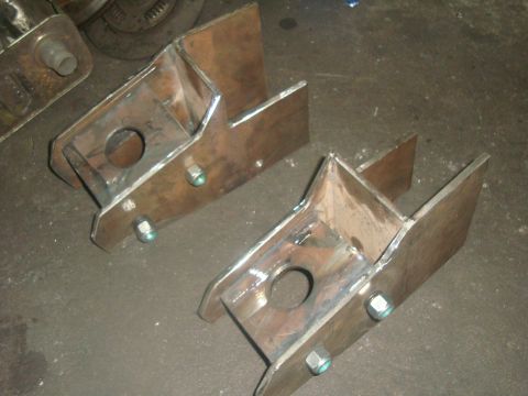 1980 Ford Bronco - Custom metal brackets, likely for a vehicle suspension or frame modification, are shown on a workshop floor.